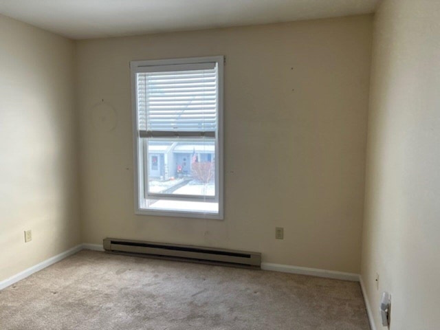 carpeted spare room with a baseboard radiator