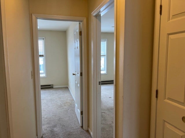 corridor with light carpet and a baseboard radiator