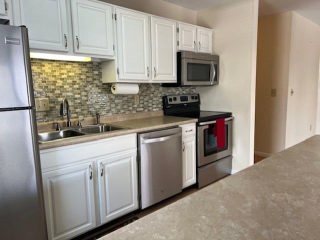 kitchen with white cabinets, sink, stainless steel appliances, and tasteful backsplash