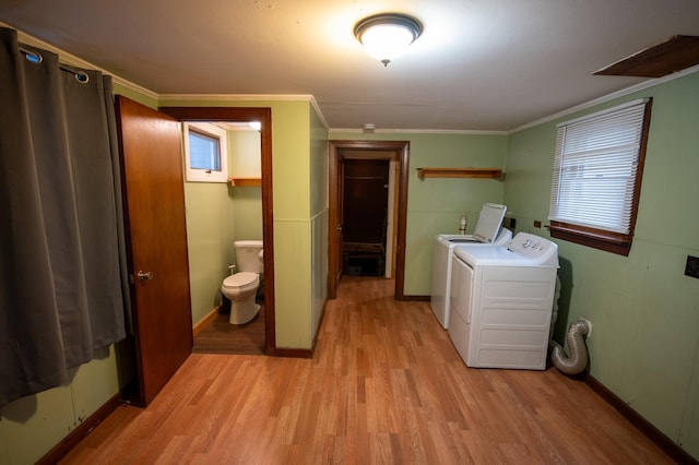 washroom with light wood-type flooring, crown molding, and washing machine and clothes dryer