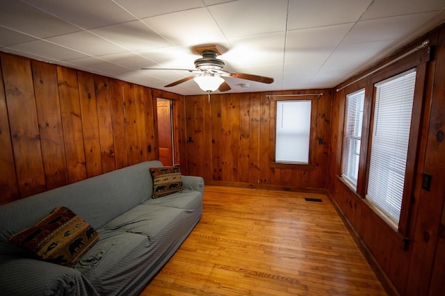 living room featuring wood walls, light hardwood / wood-style flooring, and ceiling fan