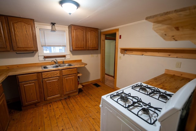 kitchen featuring sink, white range with gas stovetop, and light hardwood / wood-style flooring