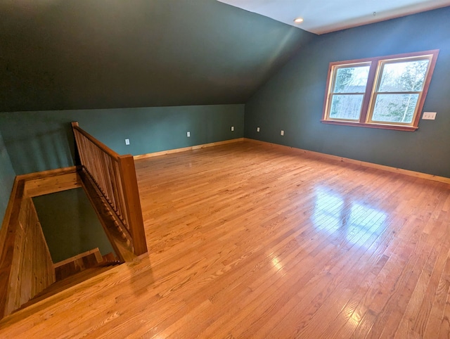 additional living space with light wood-type flooring and vaulted ceiling