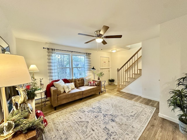 living room with ceiling fan, a baseboard radiator, and wood-type flooring