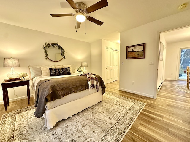 bedroom with a closet, ceiling fan, light hardwood / wood-style floors, and baseboard heating