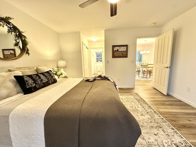 bedroom featuring ceiling fan with notable chandelier and hardwood / wood-style flooring