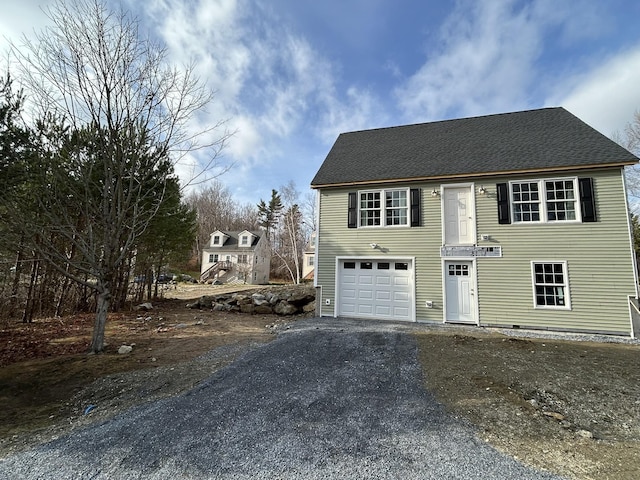 view of front of home with a garage, driveway, and roof with shingles