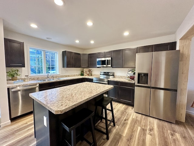 kitchen with a kitchen island, appliances with stainless steel finishes, dark brown cabinets, and a kitchen bar