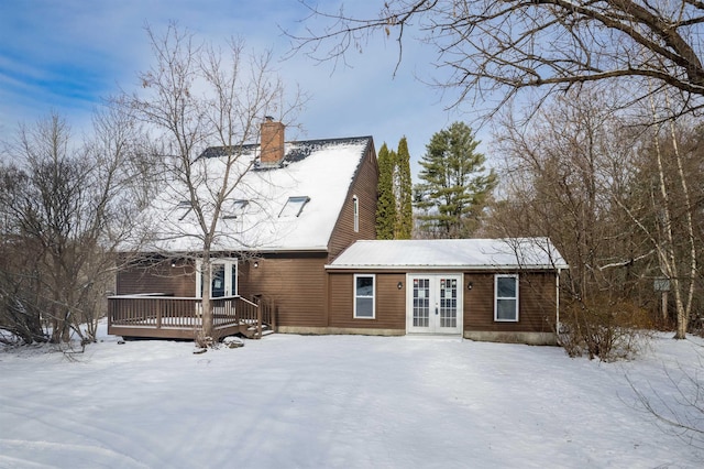 snow covered rear of property with french doors and a deck