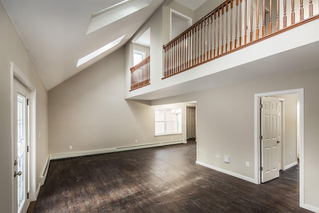 unfurnished living room featuring lofted ceiling with skylight, an inviting chandelier, dark hardwood / wood-style floors, and a baseboard heating unit