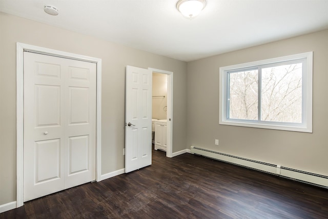 unfurnished bedroom with a baseboard radiator, ensuite bath, a closet, and dark wood-type flooring