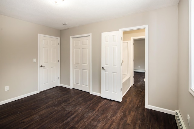 unfurnished bedroom with a textured ceiling, dark wood-type flooring, a closet, and a baseboard heating unit