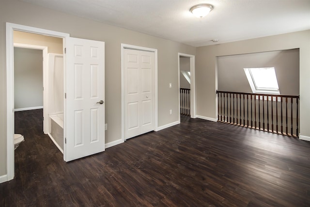 unfurnished bedroom with a skylight, a closet, dark wood-type flooring, and a textured ceiling