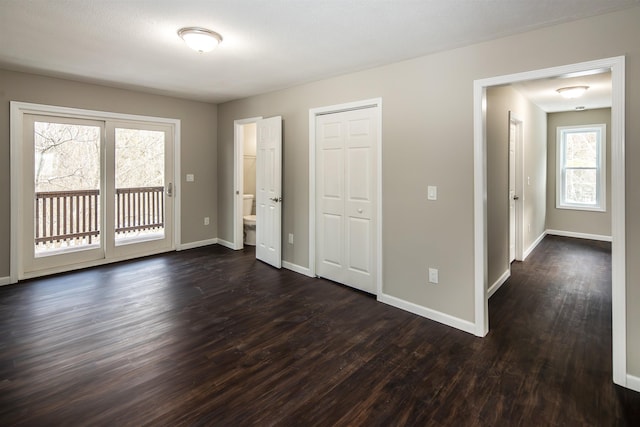 unfurnished room featuring a wealth of natural light and dark hardwood / wood-style floors