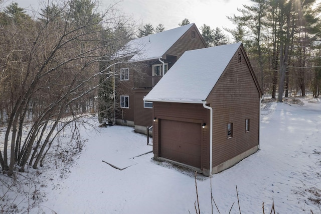 snow covered property with a balcony and a garage