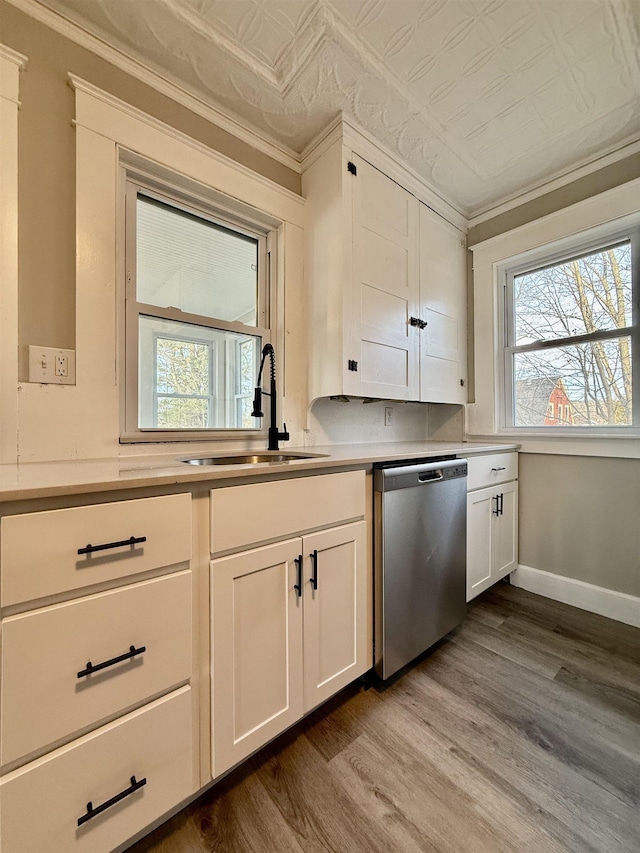 kitchen featuring dishwasher, wood-type flooring, sink, ornamental molding, and white cabinetry