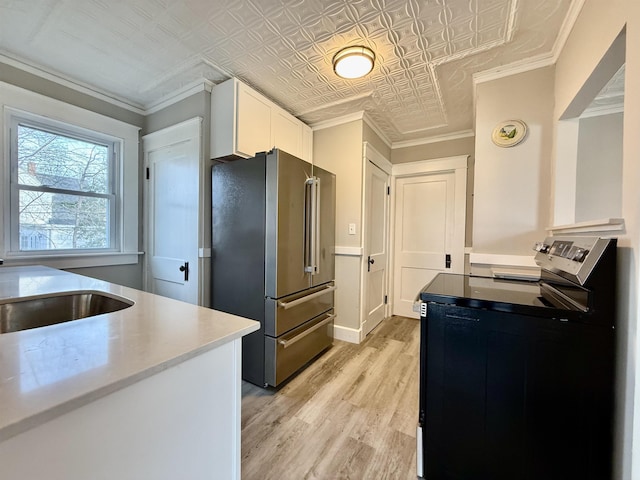 kitchen with white cabinets, electric range, light wood-type flooring, ornamental molding, and high end fridge