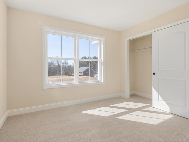 unfurnished bedroom featuring light colored carpet and a closet