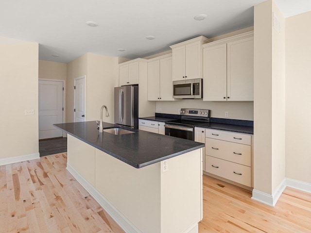 kitchen with a kitchen island with sink, light hardwood / wood-style floors, and appliances with stainless steel finishes