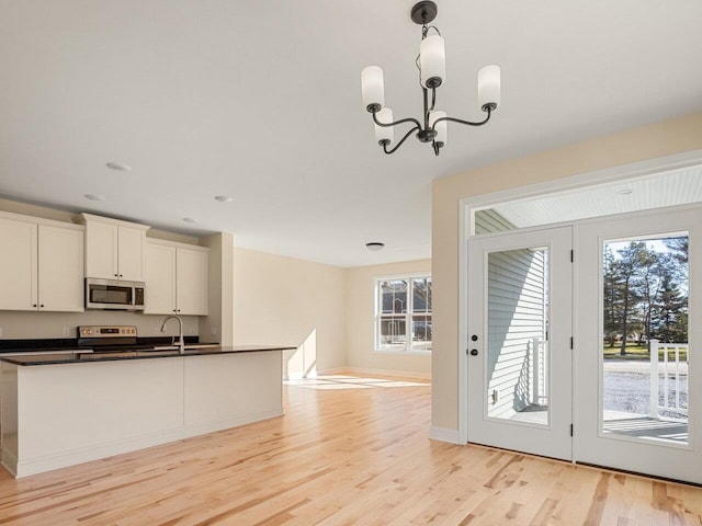 kitchen featuring light hardwood / wood-style flooring, decorative light fixtures, electric range oven, white cabinetry, and a chandelier