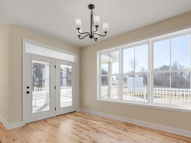 doorway to outside with a chandelier and light hardwood / wood-style flooring