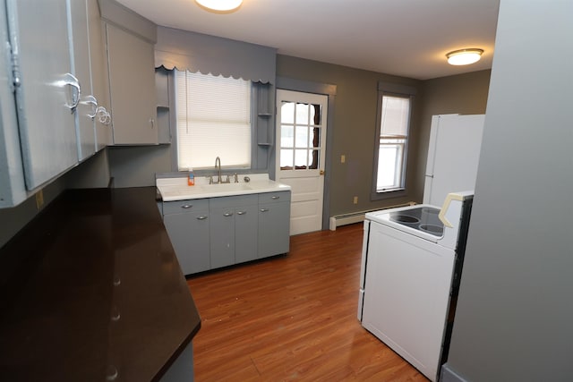 kitchen featuring white appliances, sink, a baseboard radiator, hardwood / wood-style floors, and gray cabinets