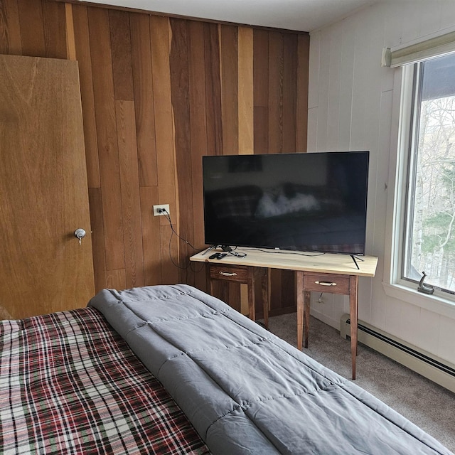 bedroom featuring baseboard heating, multiple windows, wood walls, and carpet flooring