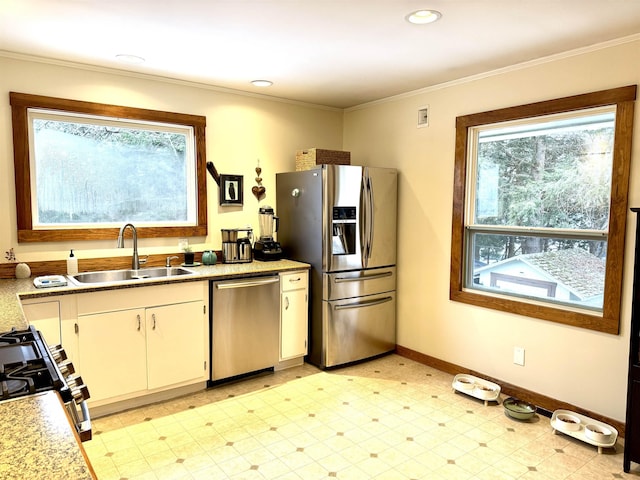 kitchen with white cabinets, stainless steel appliances, ornamental molding, and sink