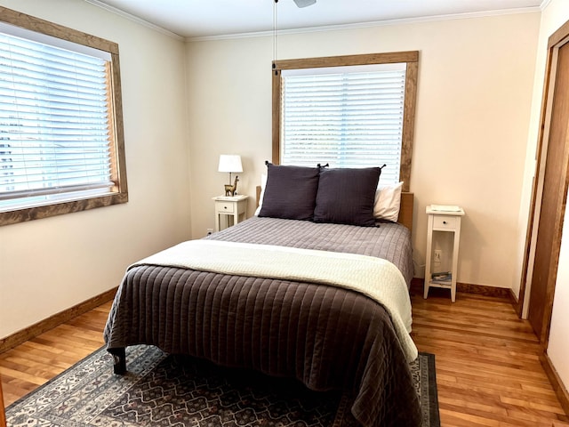 bedroom with multiple windows, wood-type flooring, and ornamental molding