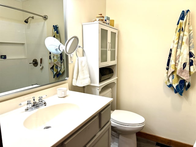 bathroom featuring toilet, a tile shower, and vanity