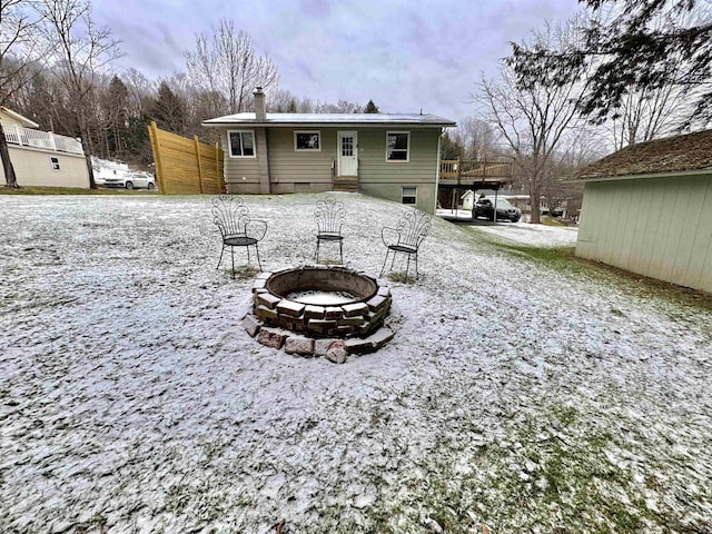 snow covered back of property with an outdoor fire pit