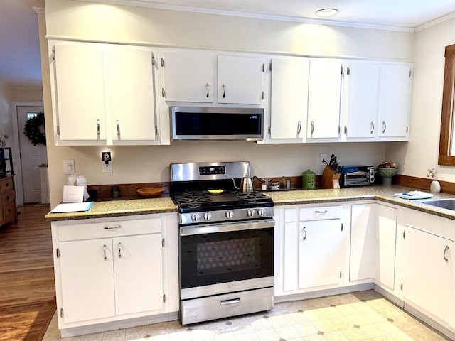 kitchen with light hardwood / wood-style floors, crown molding, white cabinetry, and stainless steel appliances