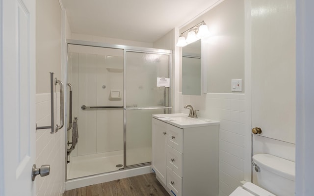 bathroom with vanity, toilet, tile walls, an enclosed shower, and wood-type flooring