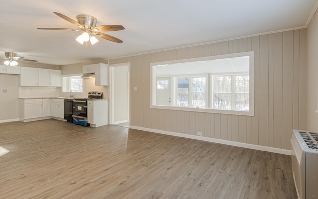 unfurnished living room with ceiling fan, sink, crown molding, wood walls, and light wood-type flooring