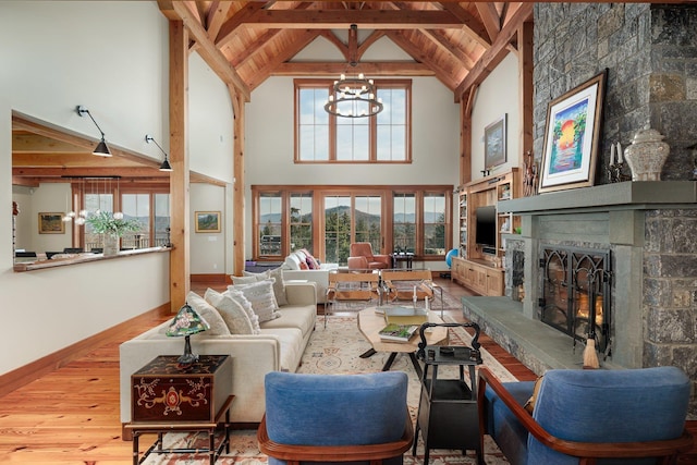 living room featuring beamed ceiling, light hardwood / wood-style flooring, a fireplace, and a healthy amount of sunlight