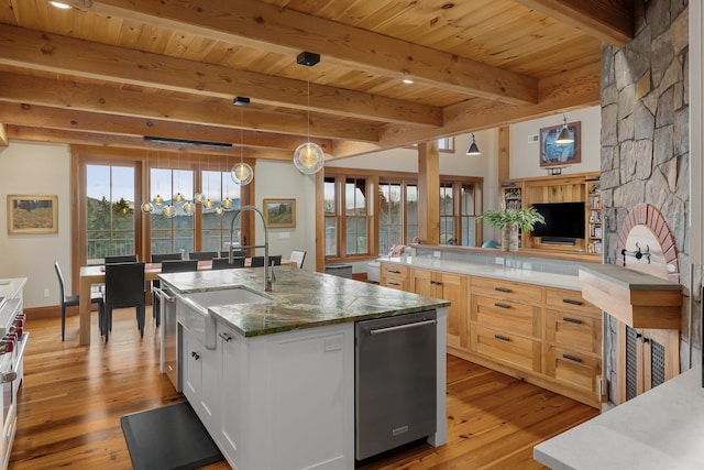 kitchen featuring beamed ceiling, decorative light fixtures, white cabinetry, and a kitchen island with sink