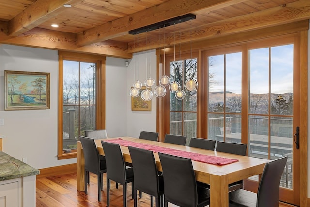 dining room with a mountain view, light hardwood / wood-style flooring, beamed ceiling, a notable chandelier, and wood ceiling