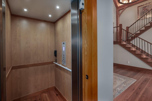 interior details featuring hardwood / wood-style floors, elevator, and ornamental molding