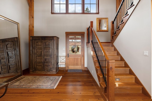 foyer entrance featuring dark hardwood / wood-style floors, a healthy amount of sunlight, and a towering ceiling