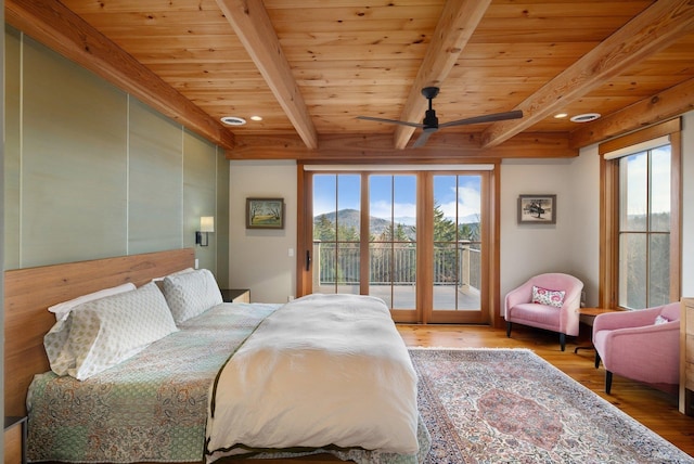 bedroom with beam ceiling, access to exterior, a mountain view, and wood-type flooring