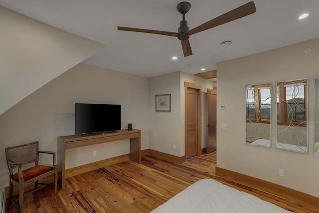 bedroom with light wood-type flooring, baseboard heating, and ceiling fan