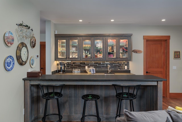 bar with hardwood / wood-style floors, sink, and tasteful backsplash