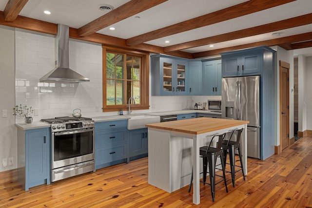 kitchen featuring blue cabinetry, sink, stainless steel appliances, and light hardwood / wood-style flooring