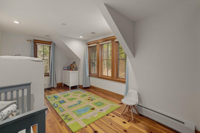 bedroom featuring hardwood / wood-style flooring and a baseboard heating unit