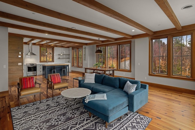 living room featuring beamed ceiling and light hardwood / wood-style floors