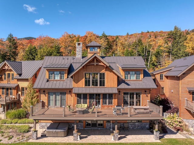 rear view of house featuring a deck, a patio, and a hot tub