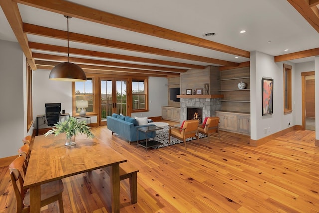 living room featuring a fireplace, french doors, light hardwood / wood-style floors, and beamed ceiling