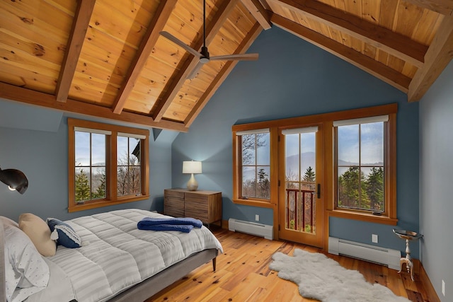 bedroom featuring beamed ceiling, multiple windows, light hardwood / wood-style flooring, and baseboard heating