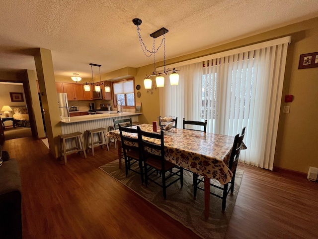 dining space featuring a textured ceiling, dark wood-style flooring, and baseboards