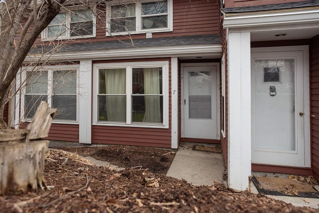 view of exterior entry with a shingled roof